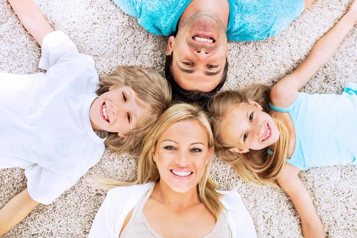 Family lying together on soft, family-friendly carpet flooring.