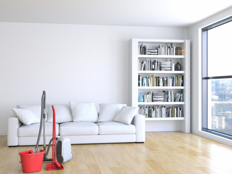 A bright room featuring white furnishings on a timber-look floor with cleaning tools.