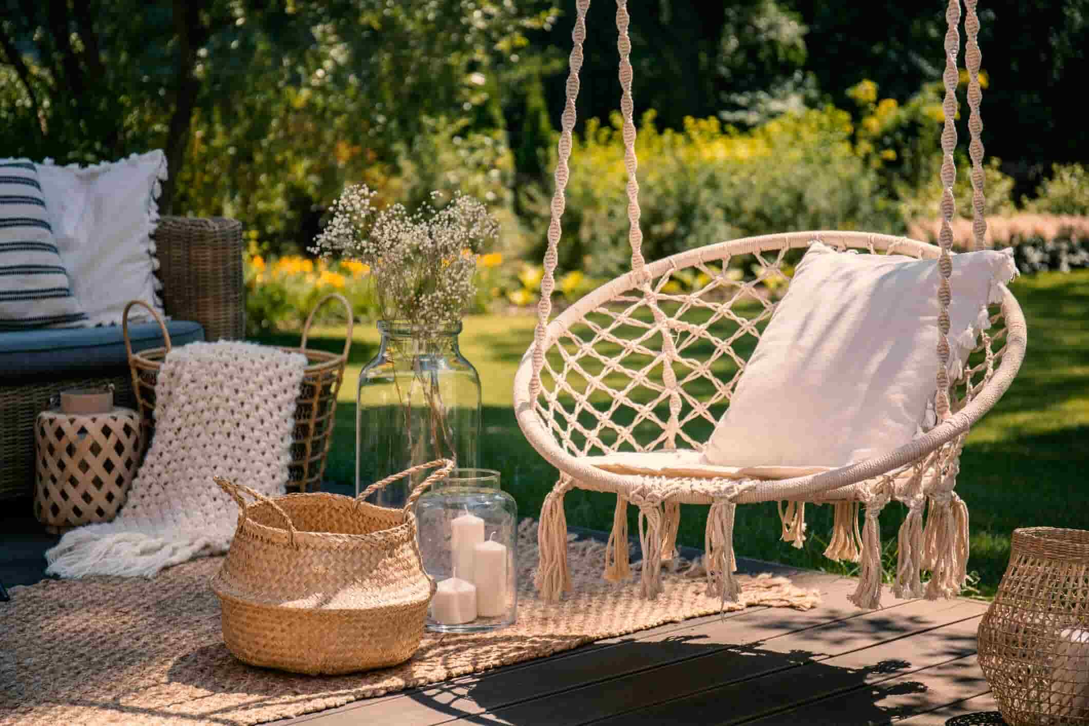 Outdoor entertaining area with hanging chair, cushions, and natural décor.