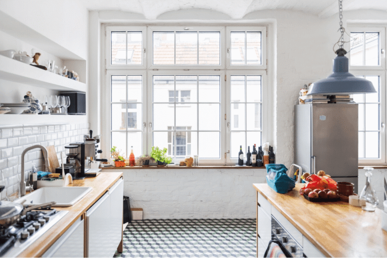 Bright kitchen with patterned tiled flooring, white cabinetry and timber benchtops.