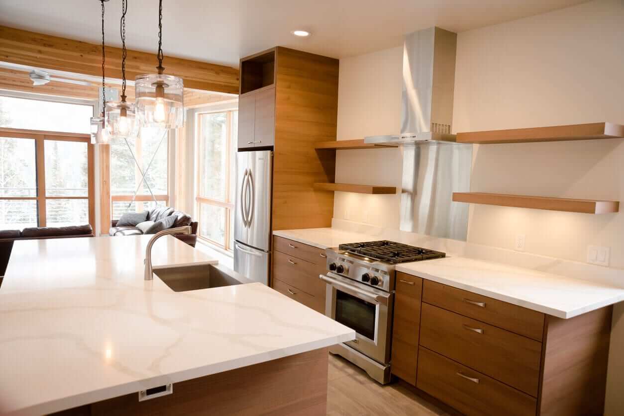 Contemporary kitchen with timber cabinetry, white stone benchtops, open shelving and stainless steel appliances in a light-filled space