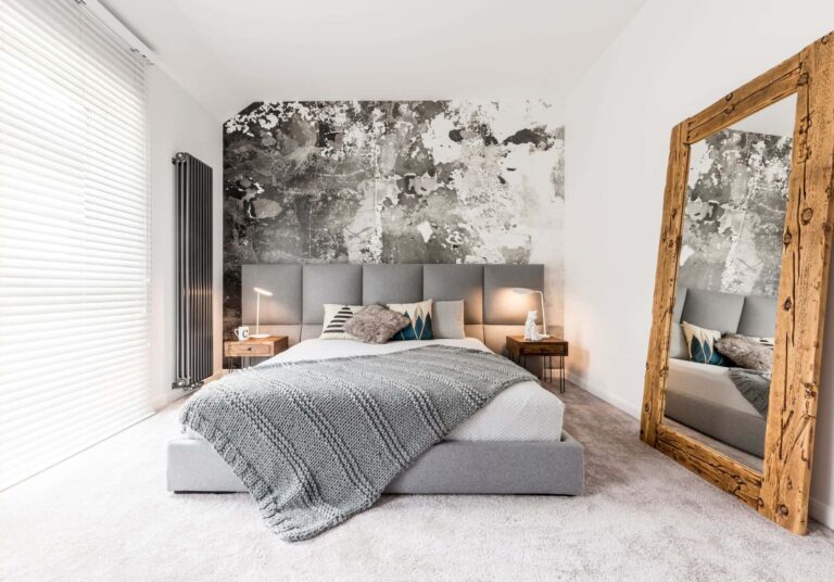 Bedroom with light wool carpet, upholstered bed and neutral styling.