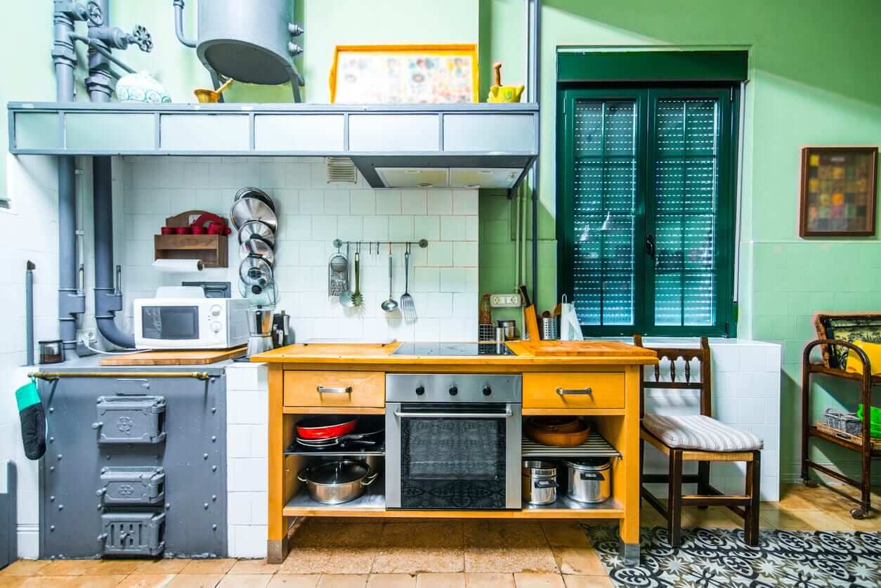 Eclectic kitchen with exposed pipes, timber workbench island, tiled splashback and vintage appliances
