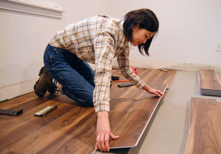 A woman installing laminate flooring planks