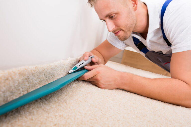 Installer cutting and fitting carpet along a wall during a flooring installation