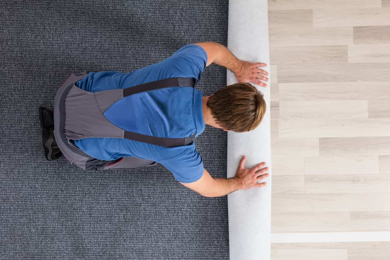 Carpet installer rolling out new carpet during professional installation.