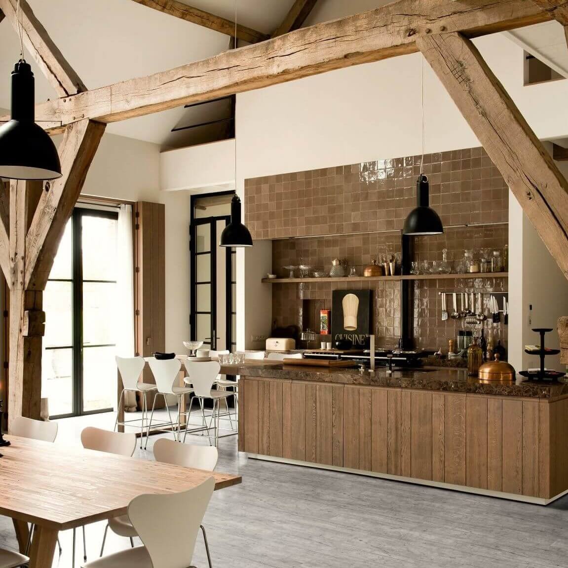Rustic open-plan kitchen featuring waterproof grey vinyl plank flooring, exposed timber ceiling beams, and a wood-paneled kitchen island.