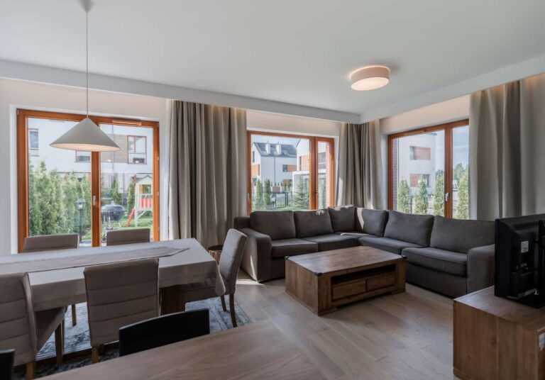 Open-plan living and dining room with light wood laminate flooring and modern furnishings