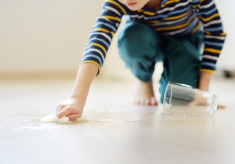 A child wiping spilled water on the floor