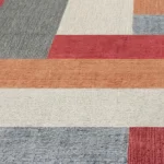 Abstract geometric carpet tiles featuring textured blocks of red, orange, grey, and cream colors, creating a modern design.