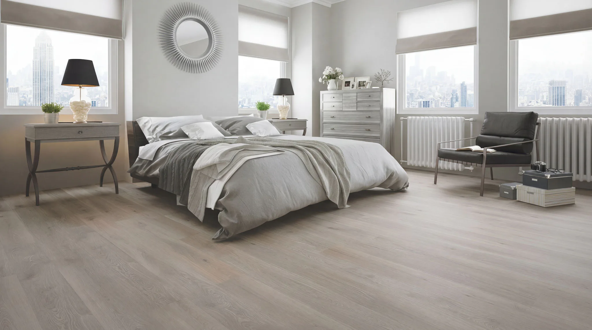 Spacious modern bedroom featuring light wood-look laminate flooring, neutral bedding, sunburst mirror, chest of drawers, and large windows overlooking city skyline