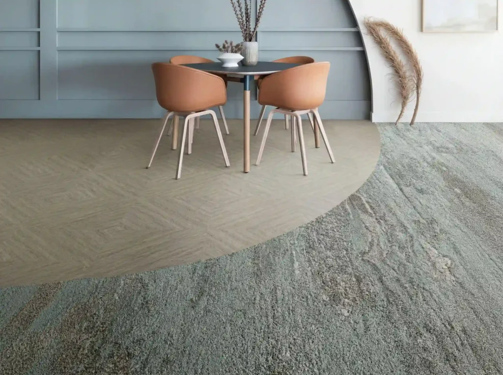 Modern flooring design featuring geometric wood look tiles and a textured green carpet area, defining a dining space.