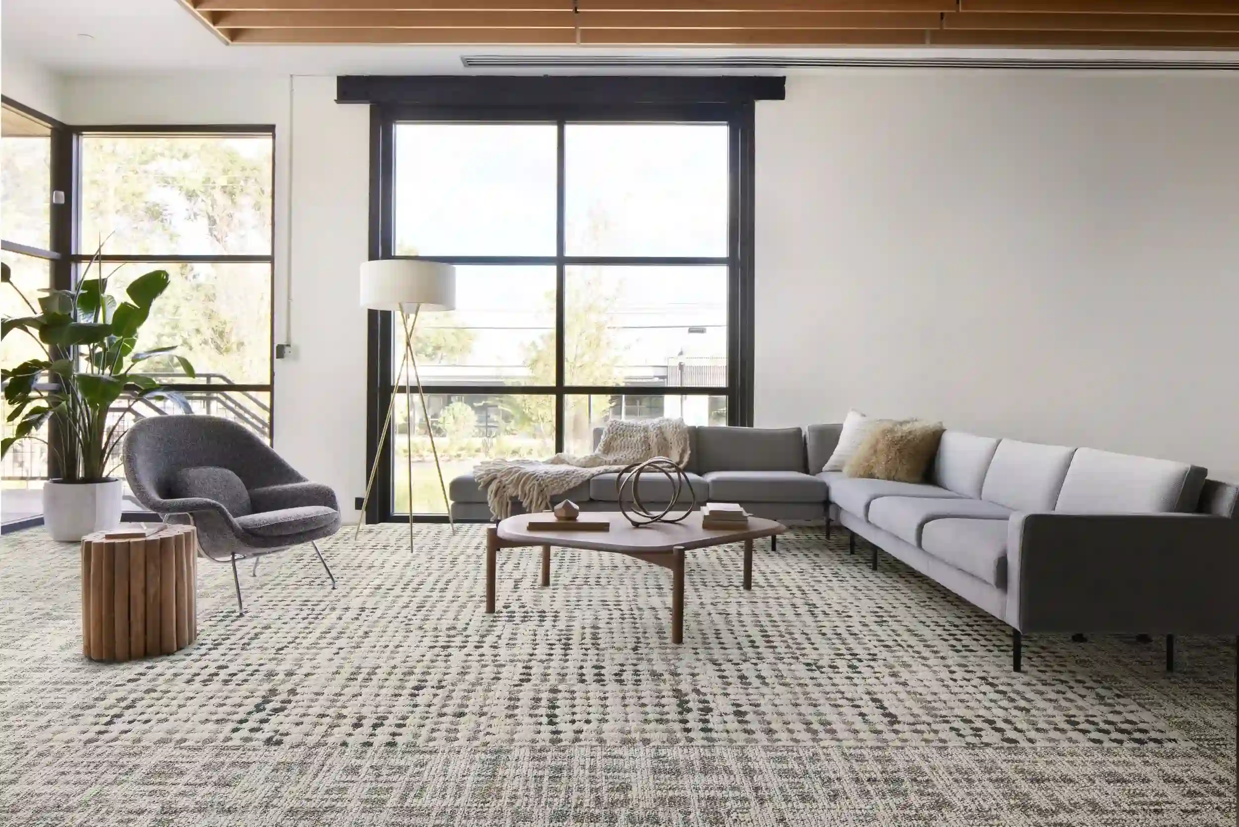 Modern living room carpet with a light gray sectional couch, a gold floor lamp, and a large window. Features a stylish, textured pattern.
