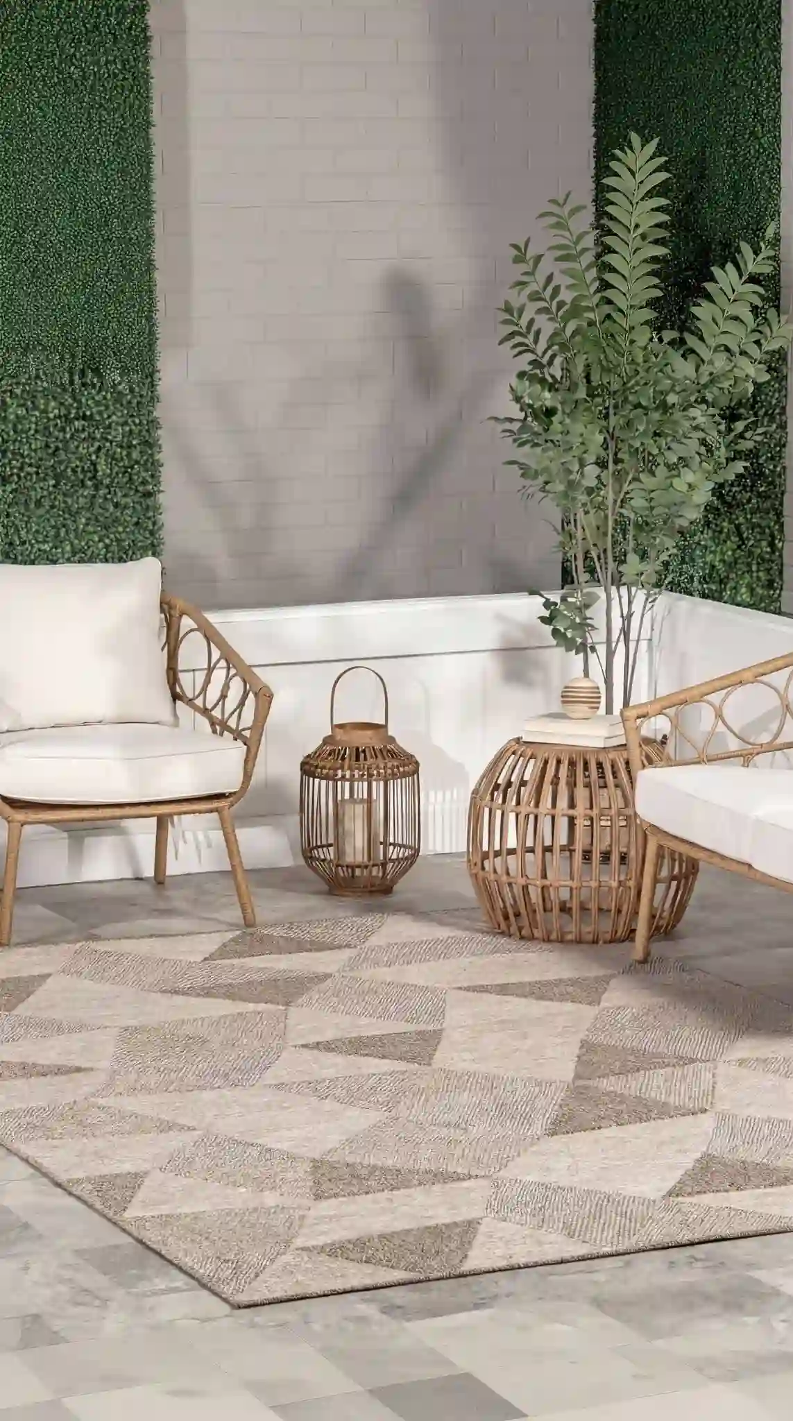 Contemporary outdoor patio featuring two rattan chairs with white cushions, wicker basket side tables, and a large geometric patterned area rug in neutral tones against artificial grass walls and w...