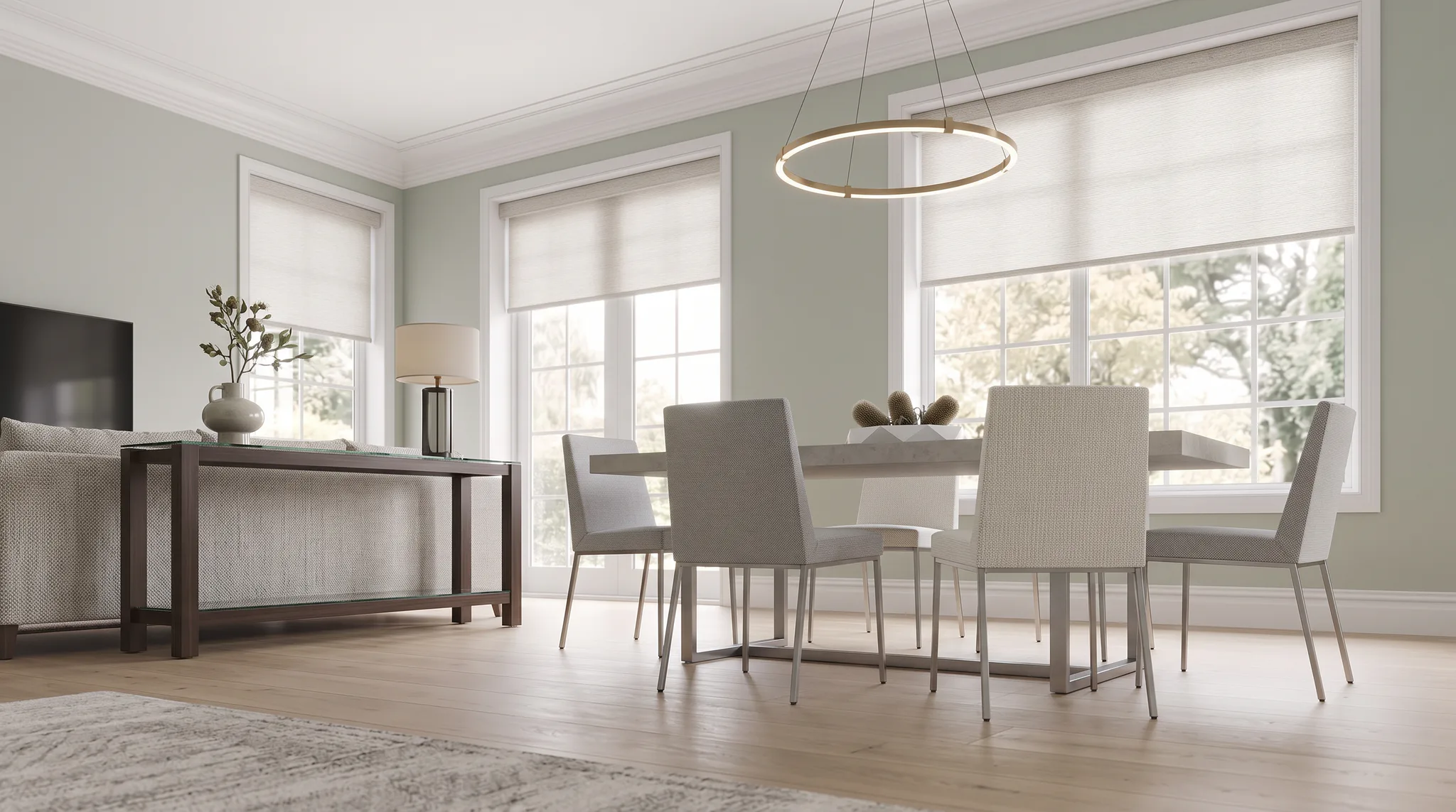Bright dining room featuring a light wood table with four upholstered chairs, pendant lighting fixture, multiple large windows with white roller shades, sage green walls, and contemporary furniture...